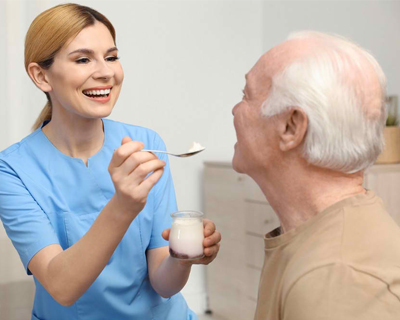 a caregiver feeding a senior man