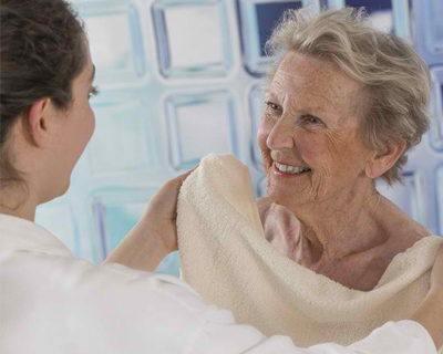 a caregiver drying a senior woman with a towel