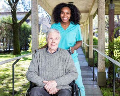 a caregiver and a senior man in wheelchair smiling